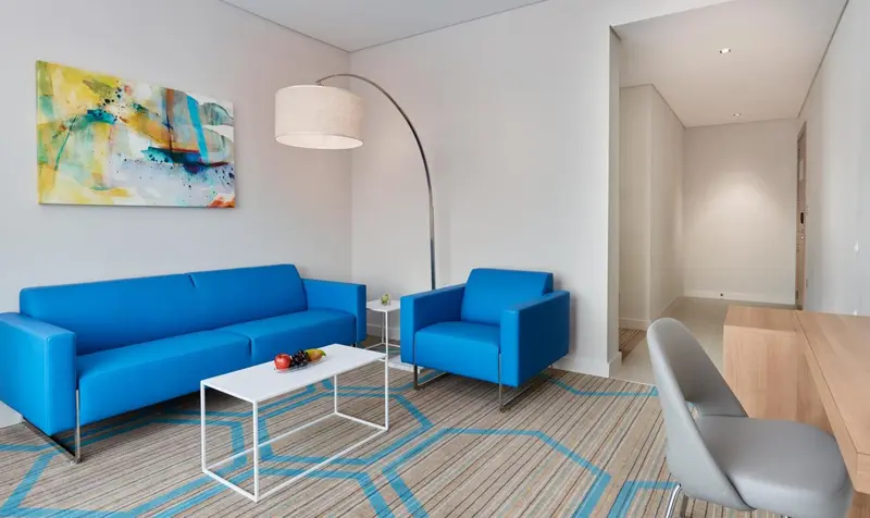 Un salon moderne avec un canapé bleu et un fauteuil assorti.