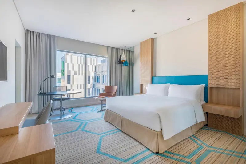 Une chambre lumineuse avec un grand lit et un bureau près d'une fenêtre.