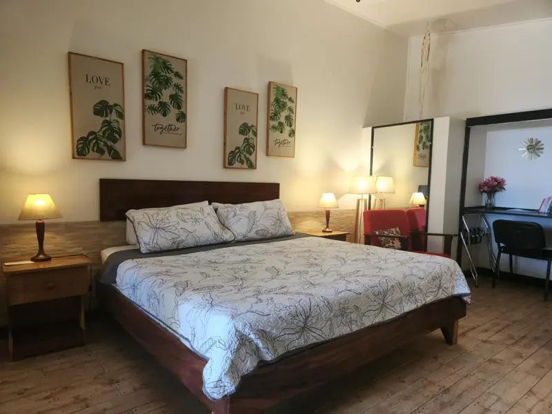 Une chambre lumineuse avec un grand lit et des illustrations florales.