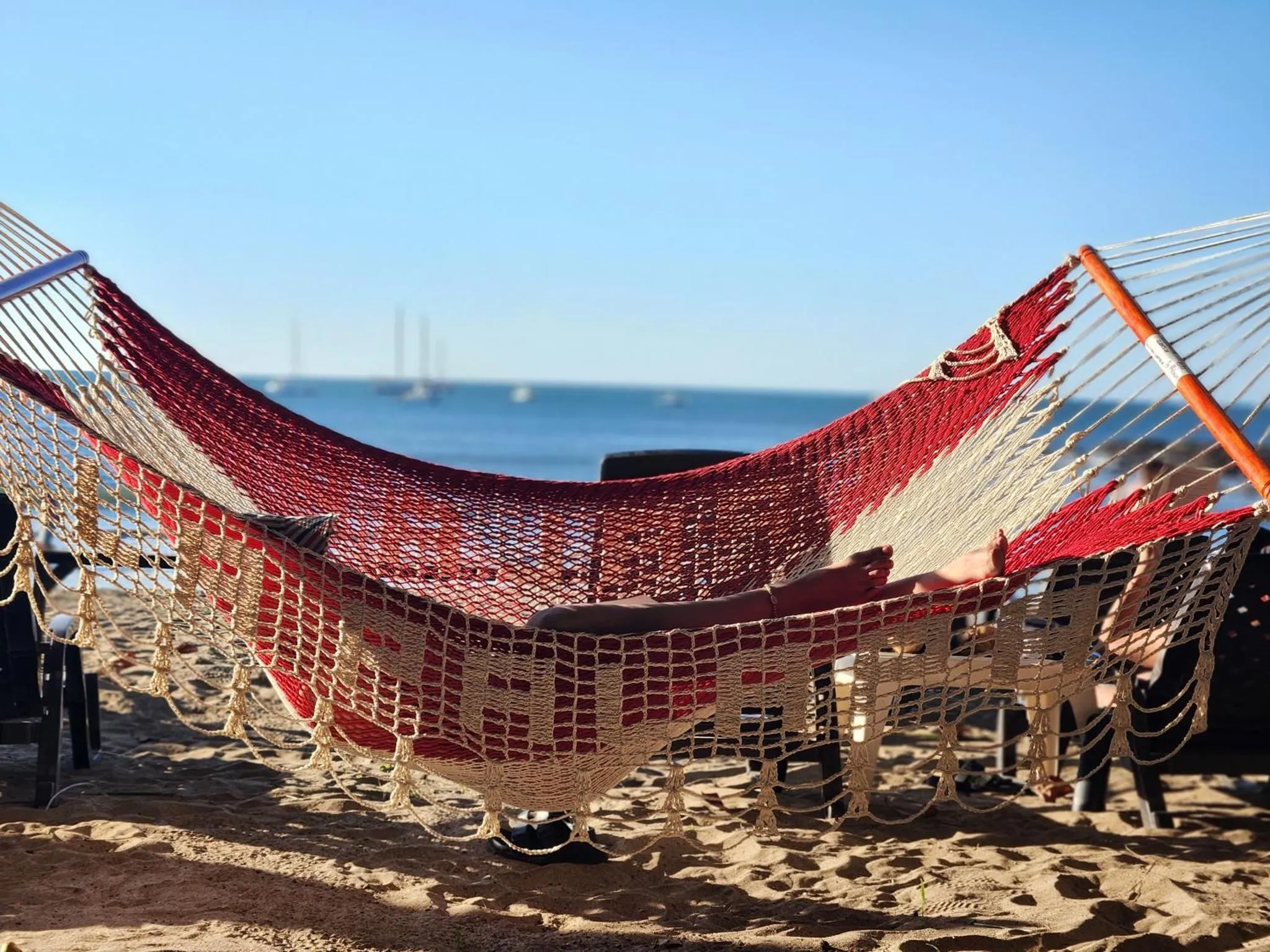 Un hamac coloré est suspendu sur une plage de sable fin face à la mer.