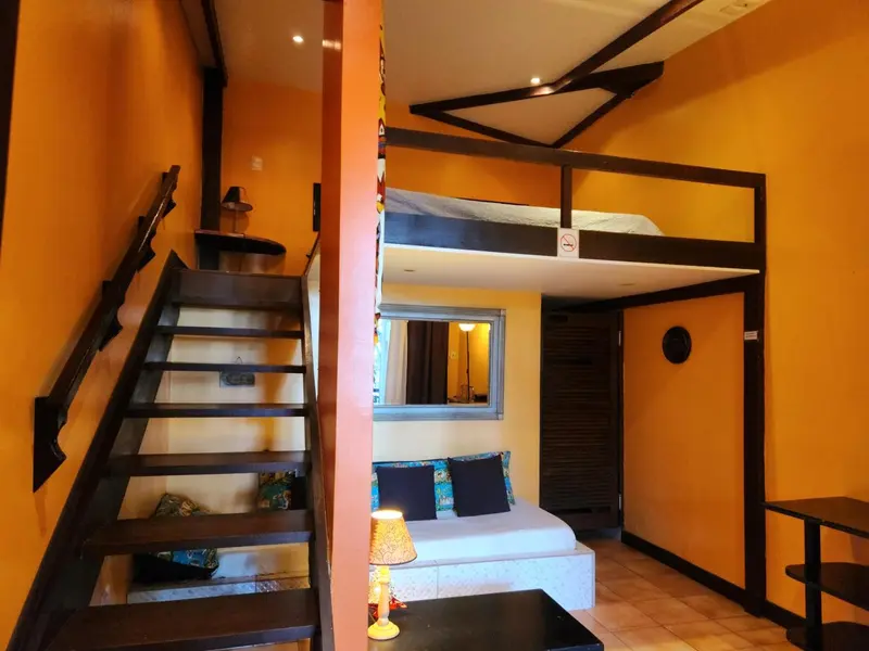 Une chambre mansardée avec un lit en mezzanine et un canapé.