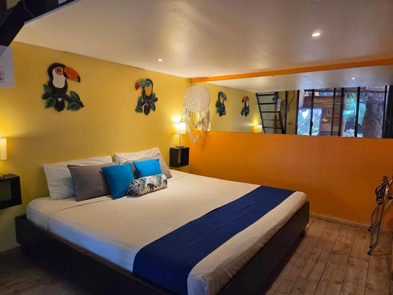Une chambre lumineuse avec un grand lit recouvert d'une courtepointe blanche et bleue.
