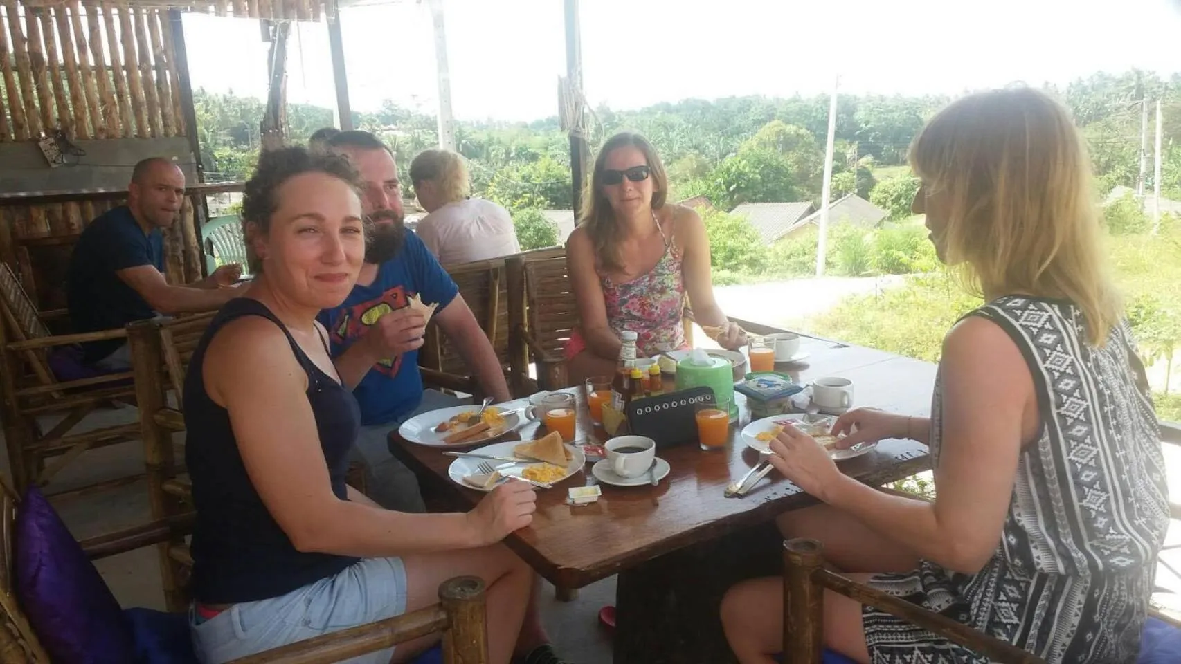 Des convives prennent leur repas sur une terrasse ombragée.