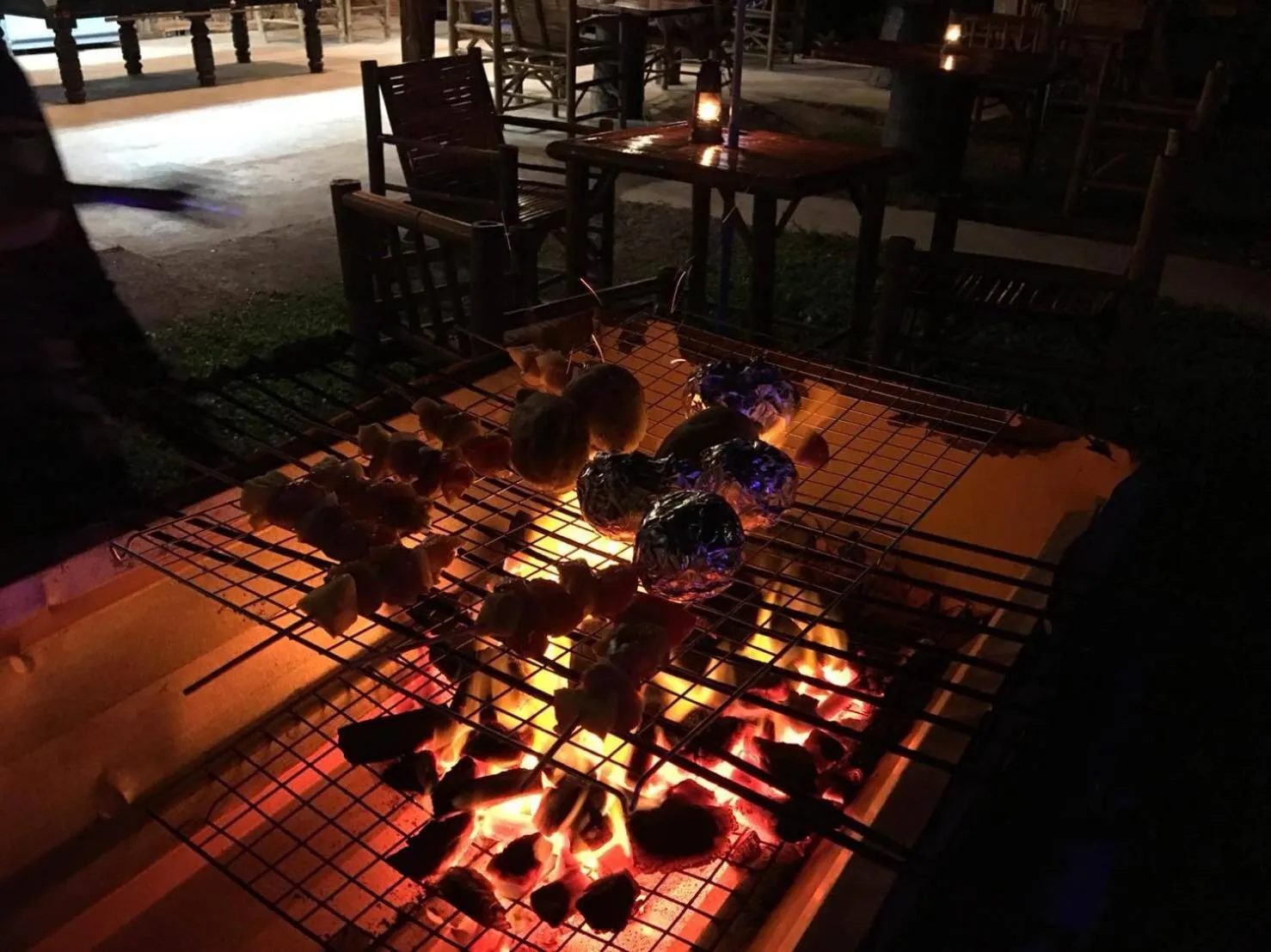 Des brochettes de nourriture grillent sur un barbecue en plein air.