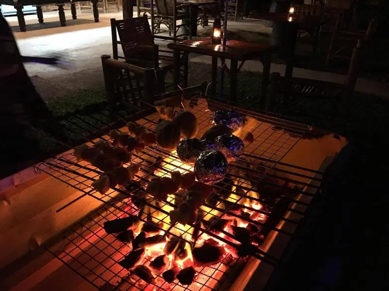Des brochettes de nourriture grillent sur un barbecue en plein air.
