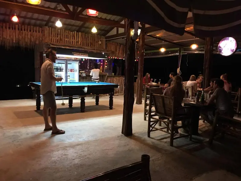 Une table de billard est installée dans un espace extérieur éclairé de guirlandes lumineuses.