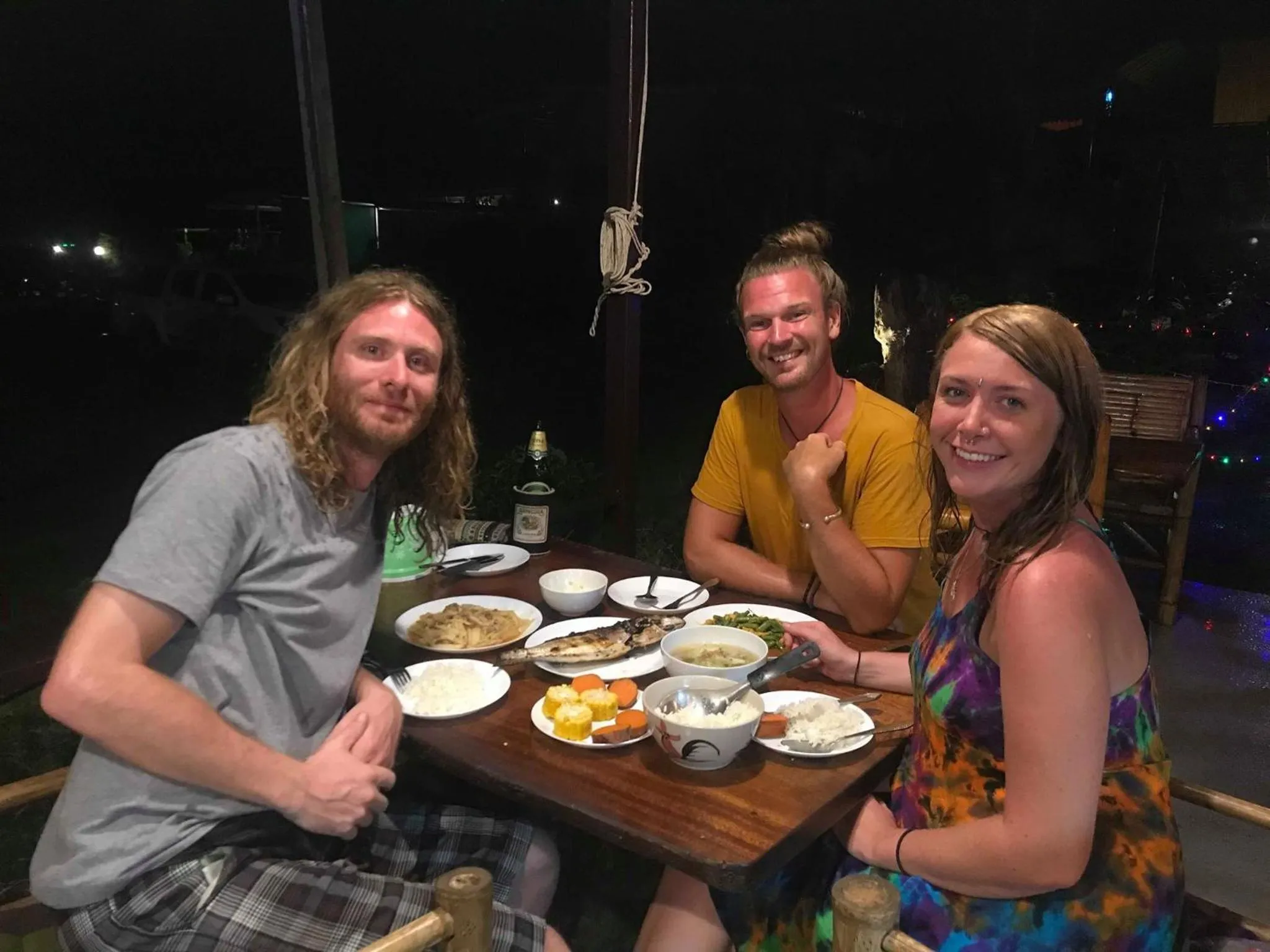 Trois personnes sourient autour d'une table garnie de plats.