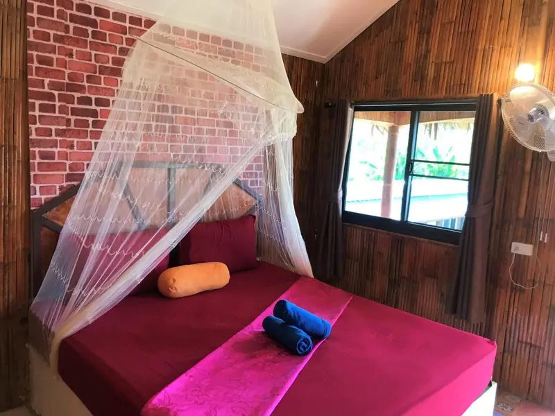 Une chambre avec un lit recouvert d'une moustiquaire et de coussins.