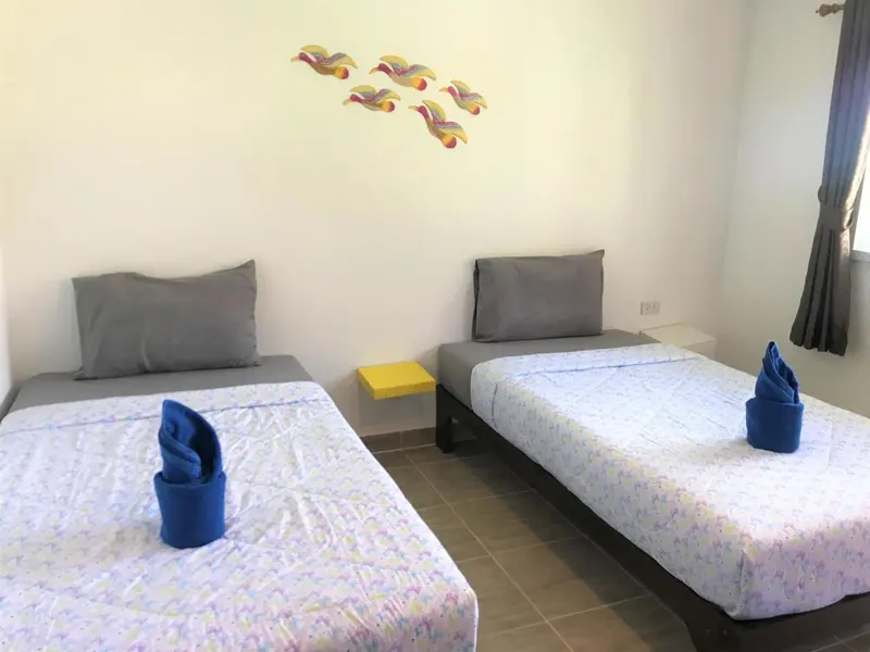 Deux lits simples dans une chambre lumineuse avec une décoration murale colorée.