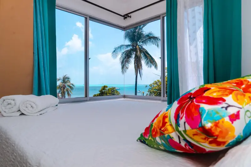 Une chambre lumineuse avec vue sur la mer et la végétation tropicale.