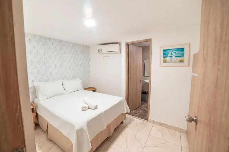Une chambre lumineuse avec un lit double et un accès à une salle de bain.