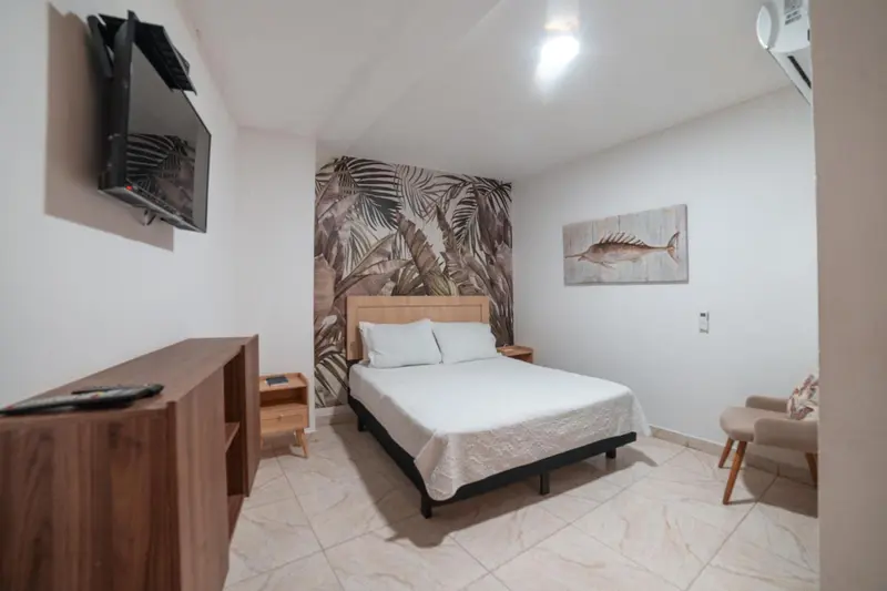 Une chambre lumineuse avec un lit double et une télévision murale.