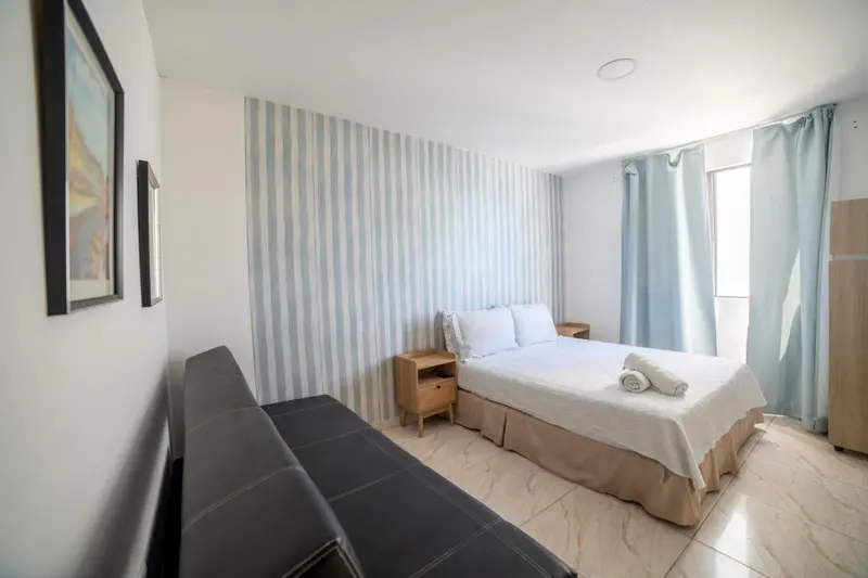 Une chambre lumineuse avec un lit double et un canapé.