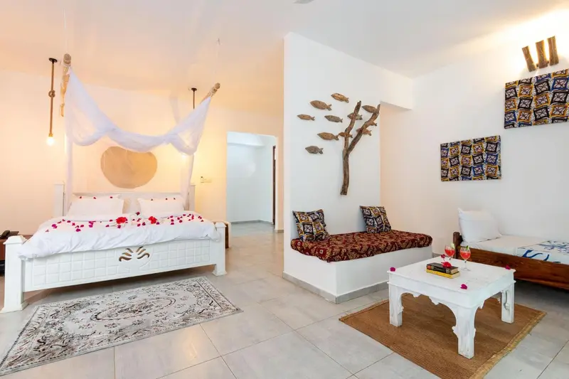 Une chambre lumineuse avec un lit à baldaquin et un coin salon.