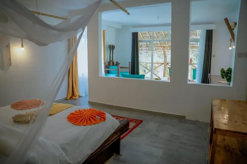 Une chambre lumineuse avec un lit recouvert d'une moustiquaire et un tapis coloré.