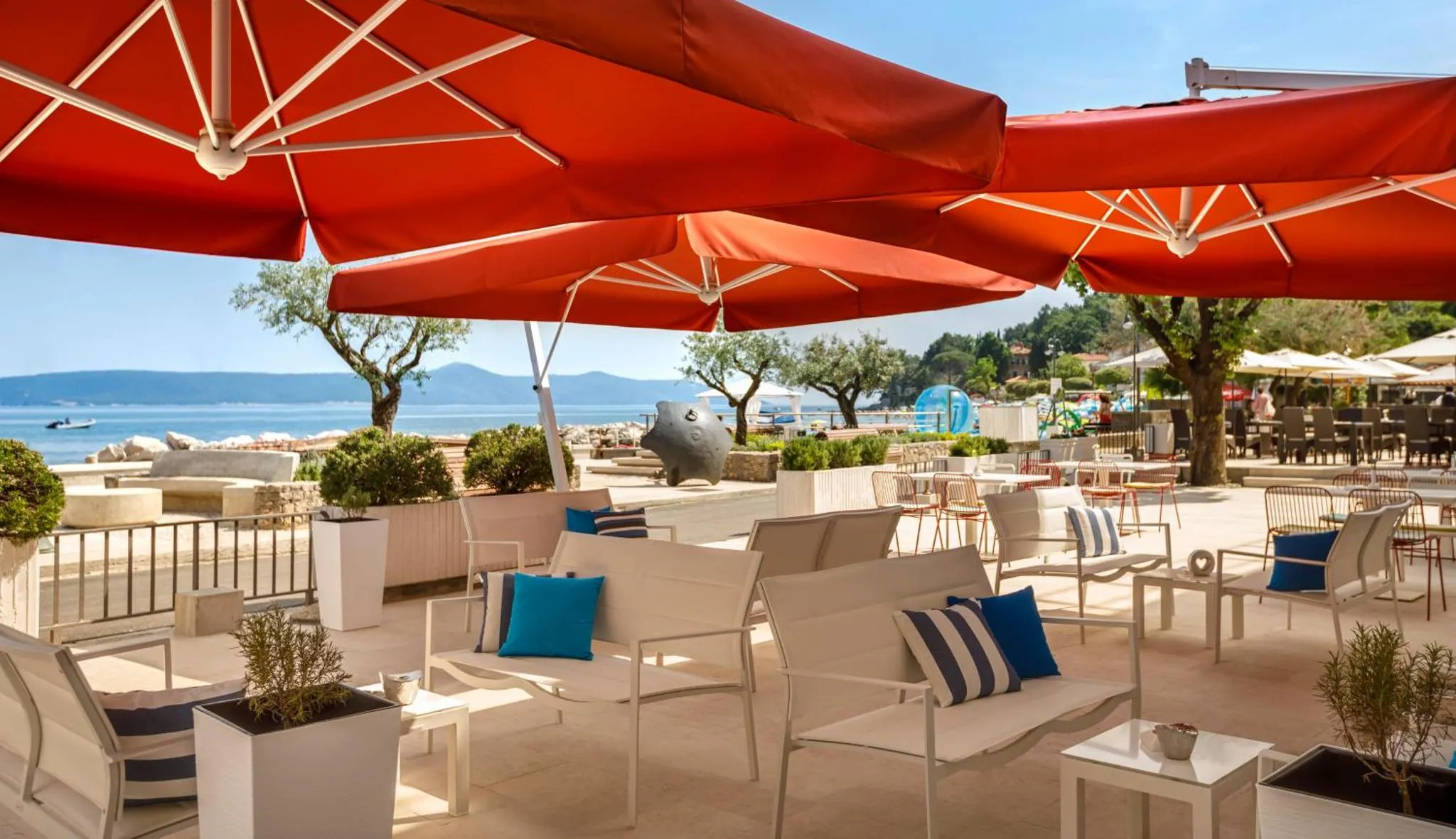 Terrasse ombragée avec mobilier d'extérieur et vue sur la mer.
