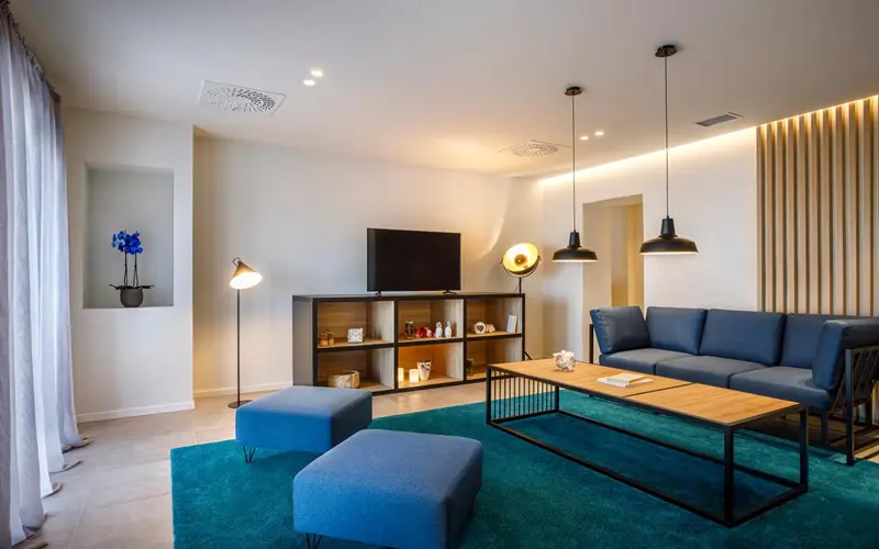 Un salon moderne avec canapé bleu et tapis turquoise.
