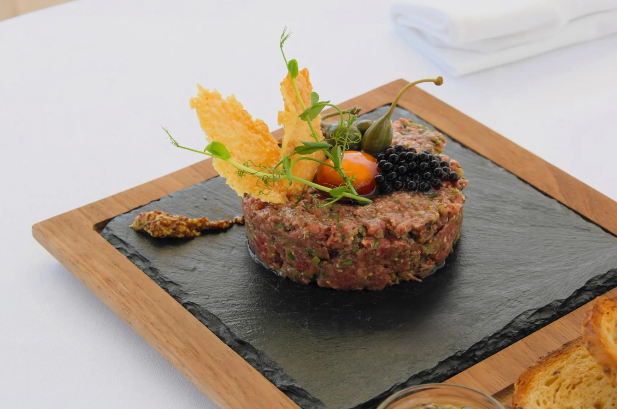 Assiette de tartare de boeuf décoré de légumes et de caviar.