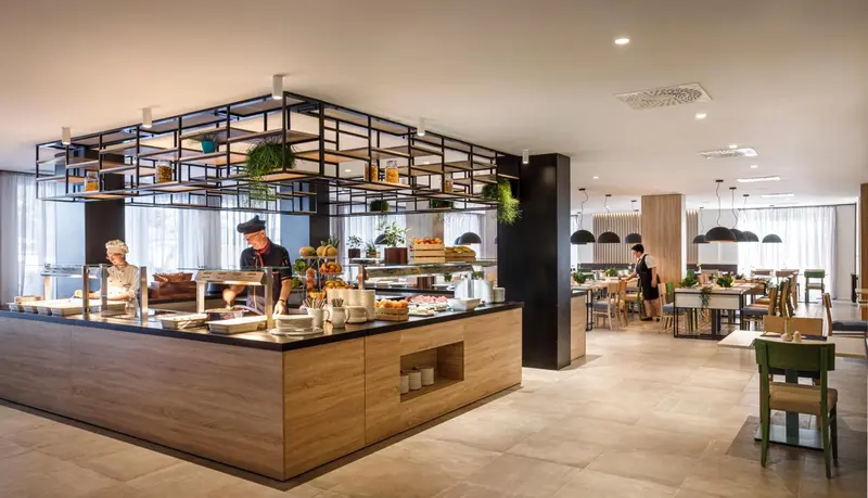 Une salle lumineuse avec un buffet de nourriture et des tables à manger.