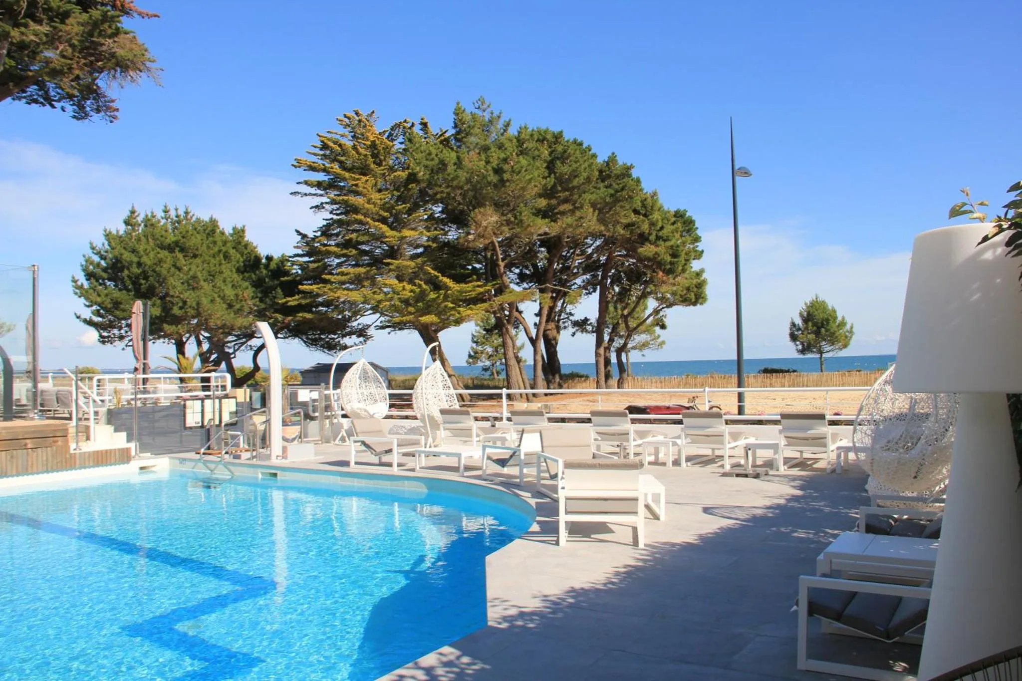 Terrasse avec piscine et mobilier de détente en bord de mer.