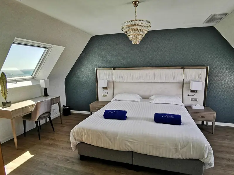 Une chambre lumineuse avec un grand lit et un bureau près d'une fenêtre.