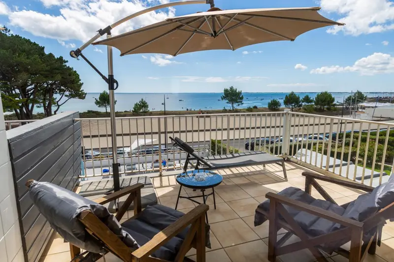 Terrasse aménagée avec mobilier de jardin donnant sur la mer.