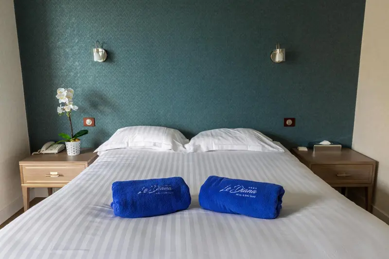 Lit double préparé avec soin dans une chambre aux murs bleus.