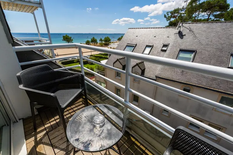 Une terrasse avec mobilier d'extérieur offre une vue sur la mer et les toits.