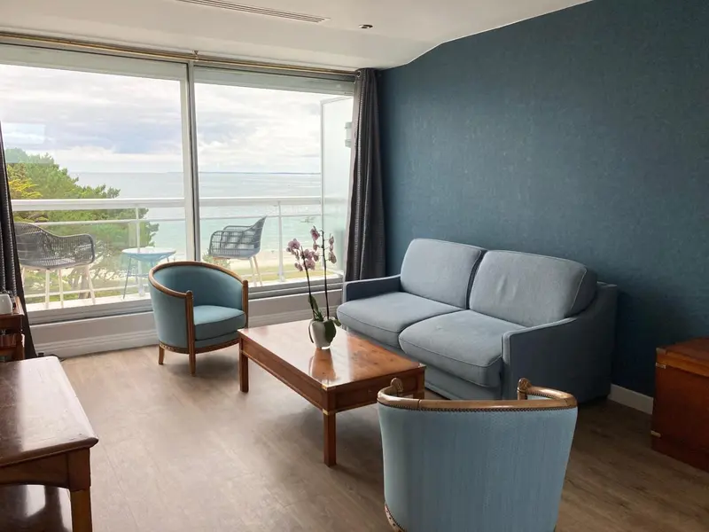 Un salon lumineux avec canapé et fauteuils donnant sur une vue mer.
