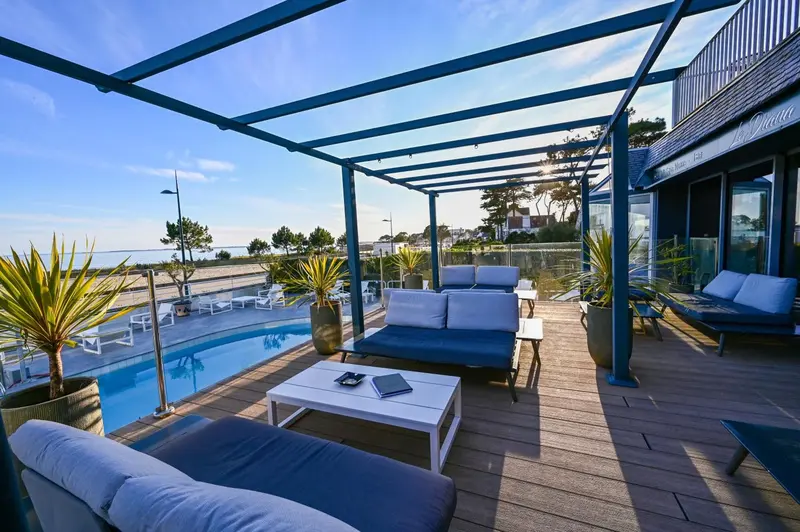Terrasse aménagée avec salon et piscine au bord de la mer.