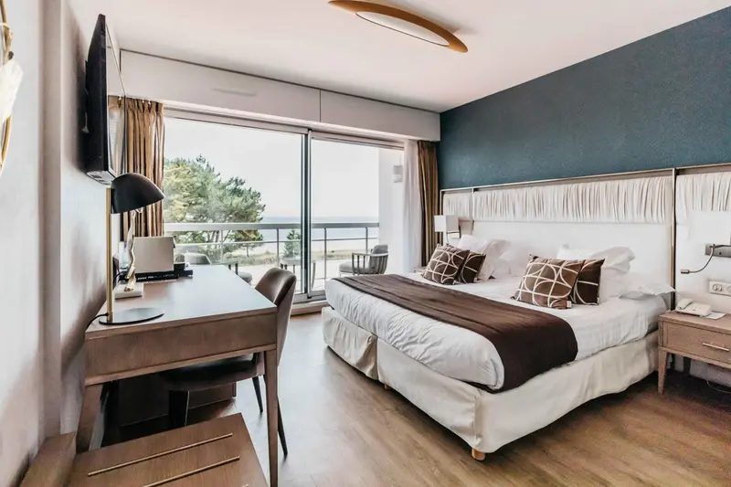 Chambre lumineuse avec un grand lit et une vue sur la mer.