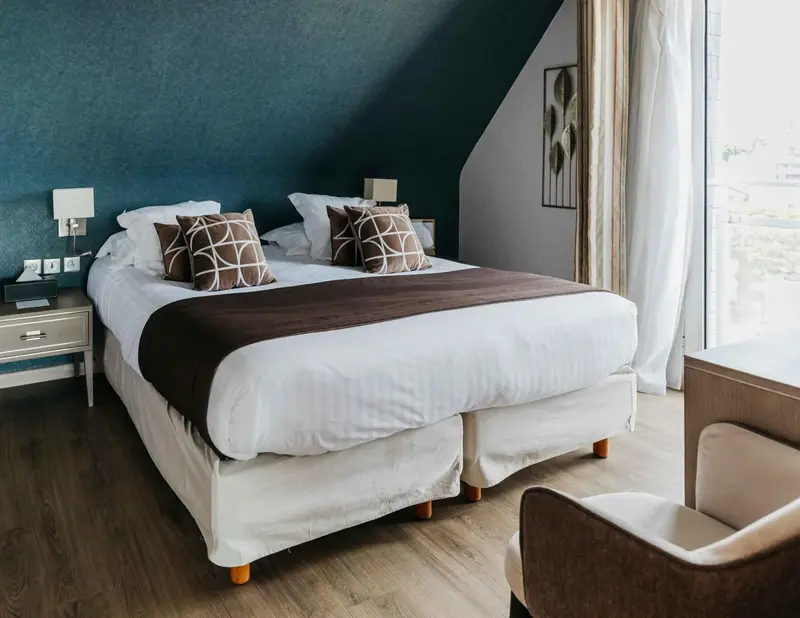 Une chambre lumineuse avec un grand lit recouvert d'une courtepointe.