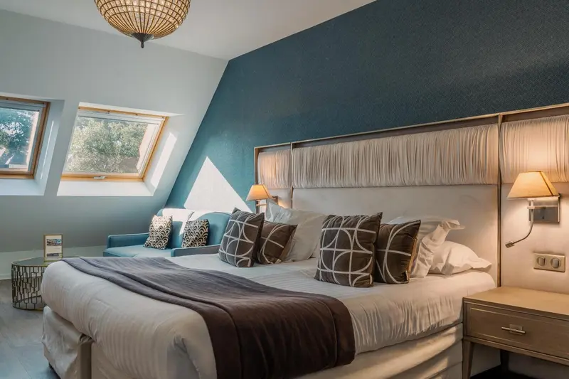 Une chambre lumineuse avec un grand lit et un coin salon.