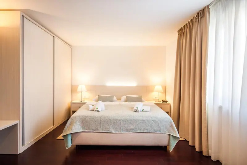Une chambre lumineuse avec un grand lit et des rideaux beiges.