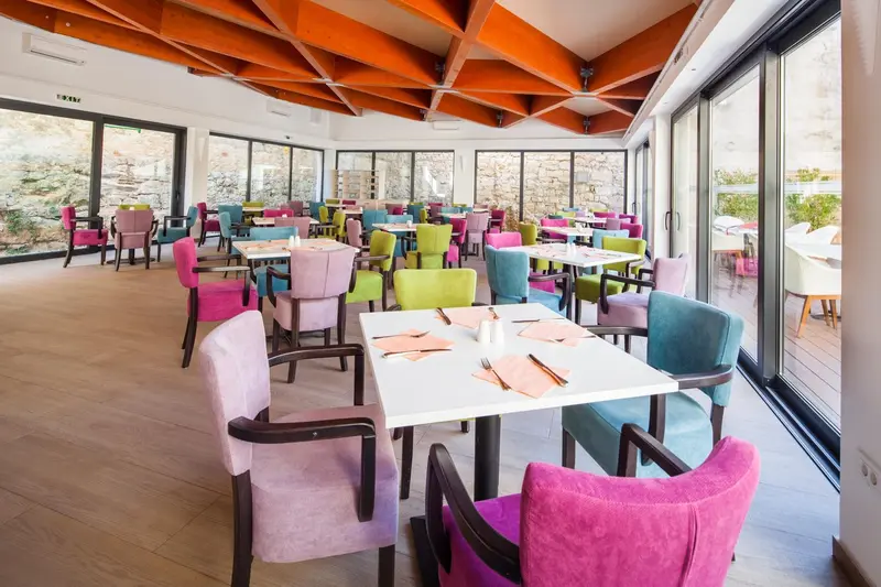 Une salle lumineuse avec des tables et des chaises colorées est prête pour le service.