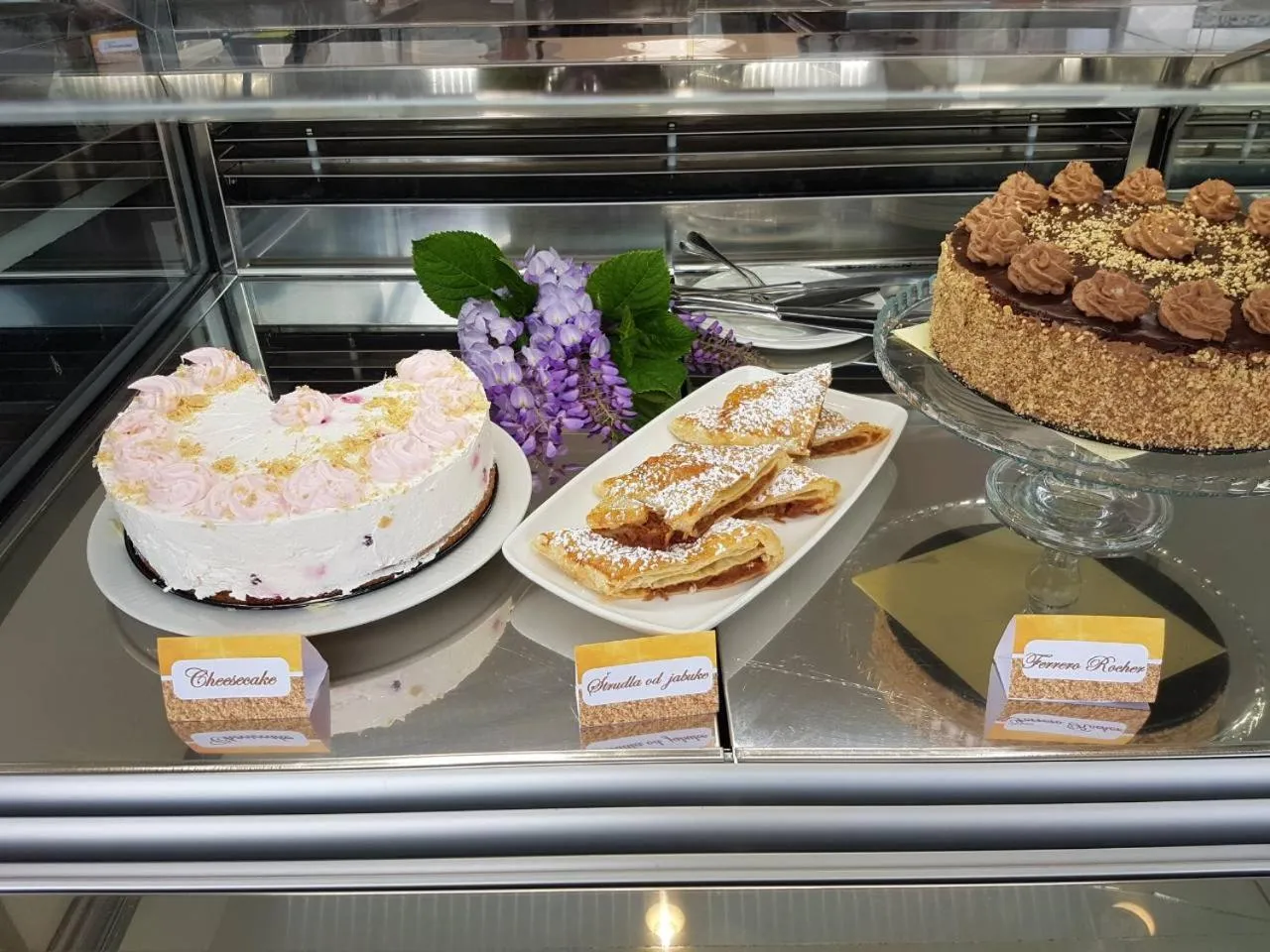 Présentation de pâtisseries variées dans une vitrine réfrigérée.