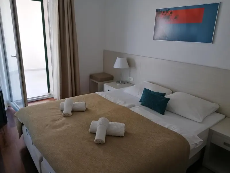 Une chambre lumineuse avec un grand lit et un accès à un balcon.