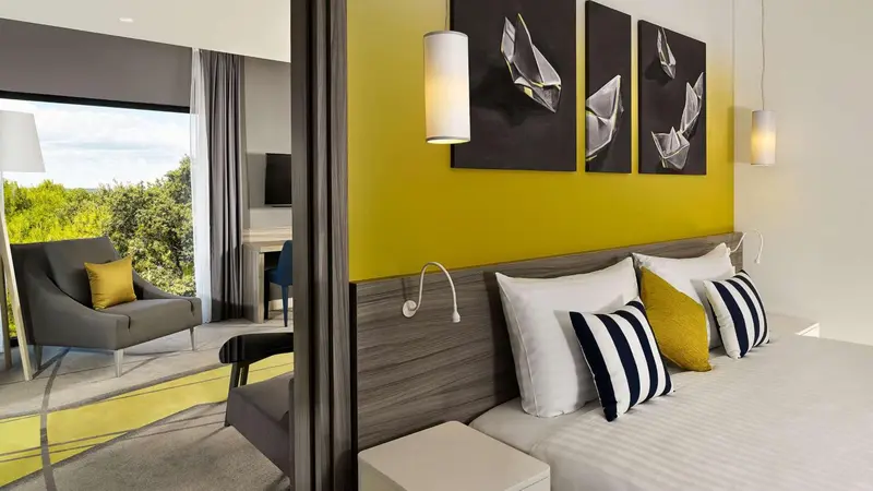 Une chambre lumineuse avec un espace salon et une vue sur la végétation.