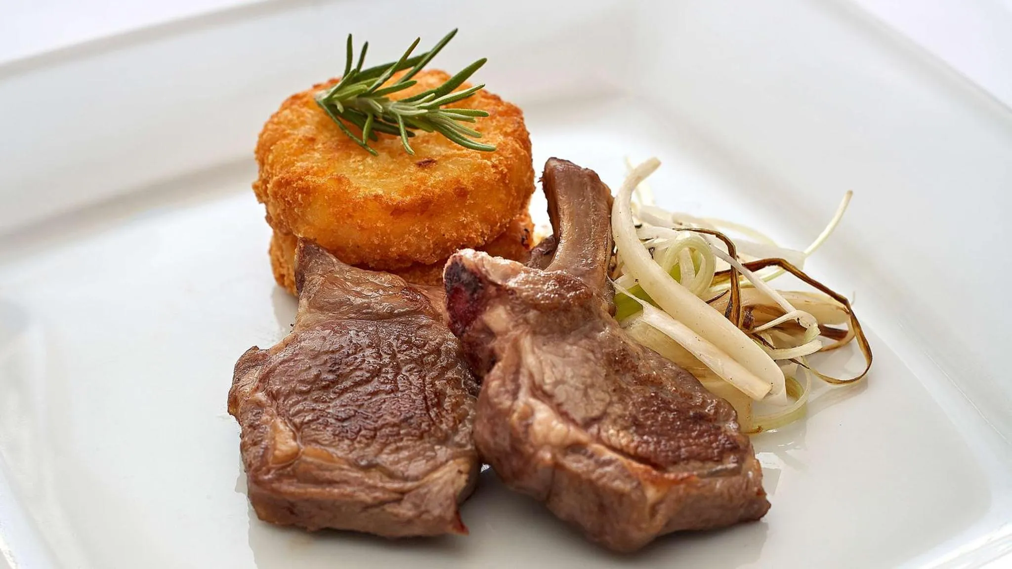 Assiette de viande grillée accompagnée d'une galette de pommes de terre et de légumes.