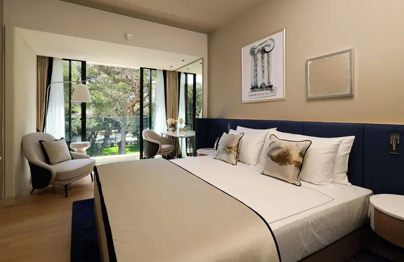 Une chambre lumineuse avec un grand lit et un coin salon près d'une fenêtre.