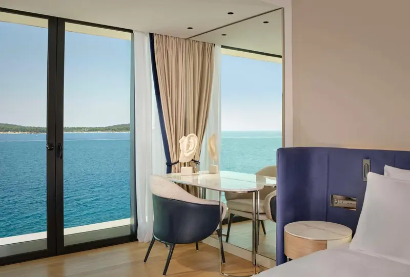Une chambre lumineuse avec vue sur la mer depuis de grandes baies vitrées.