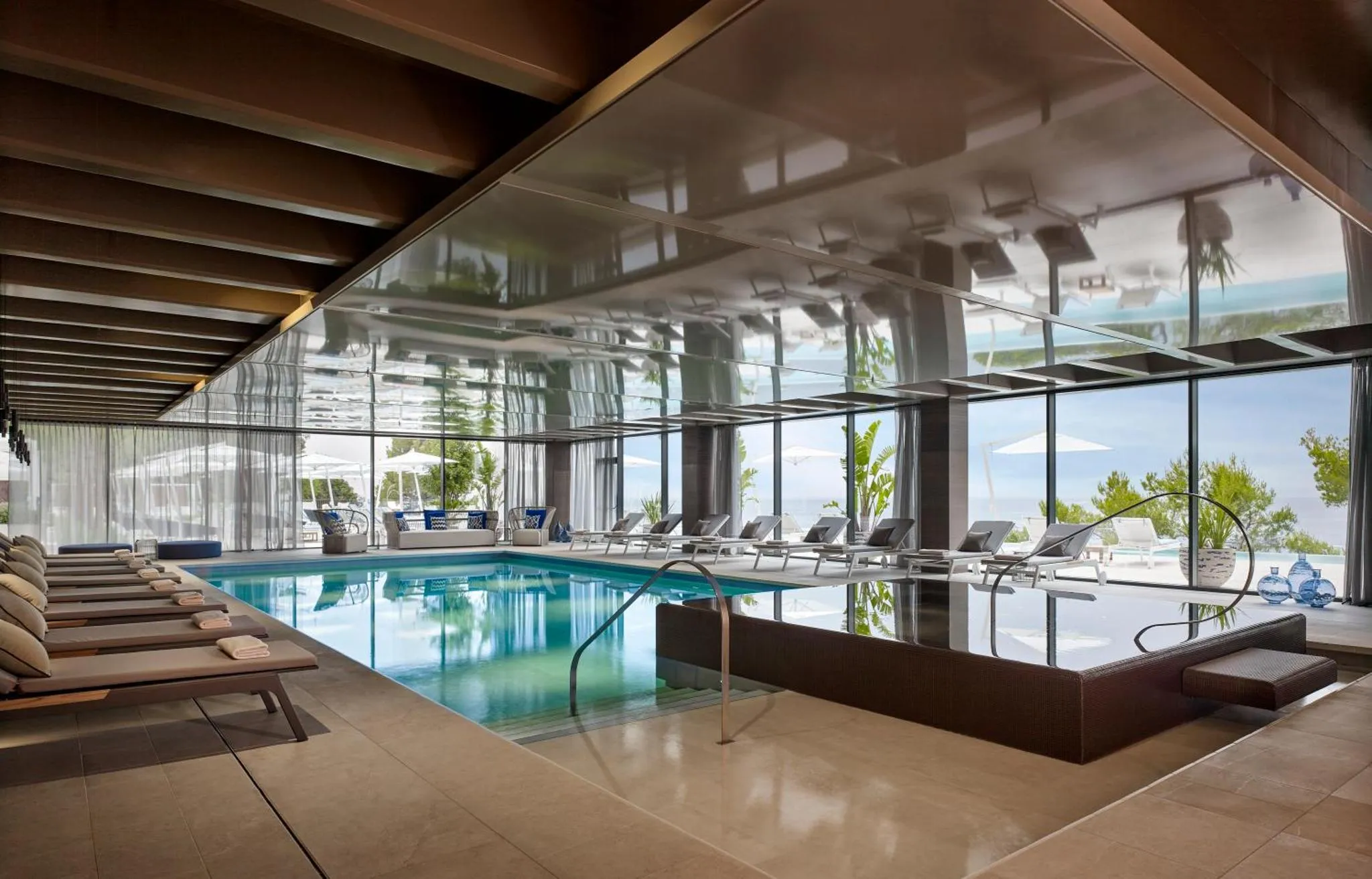 Une piscine interieure avec des transats et une vue sur la mer.