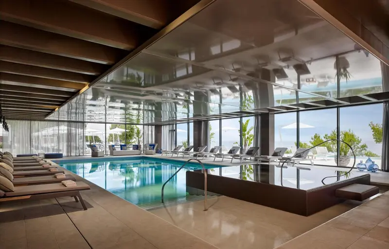 Une piscine interieure avec des transats et une vue sur la mer.