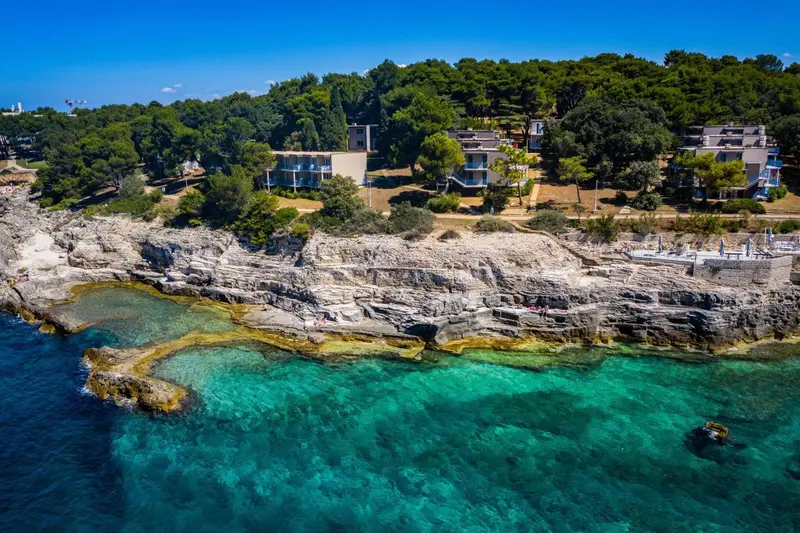 Vue aérienne d'un établissement sur une côte rocheuse avec une eau turquoise.