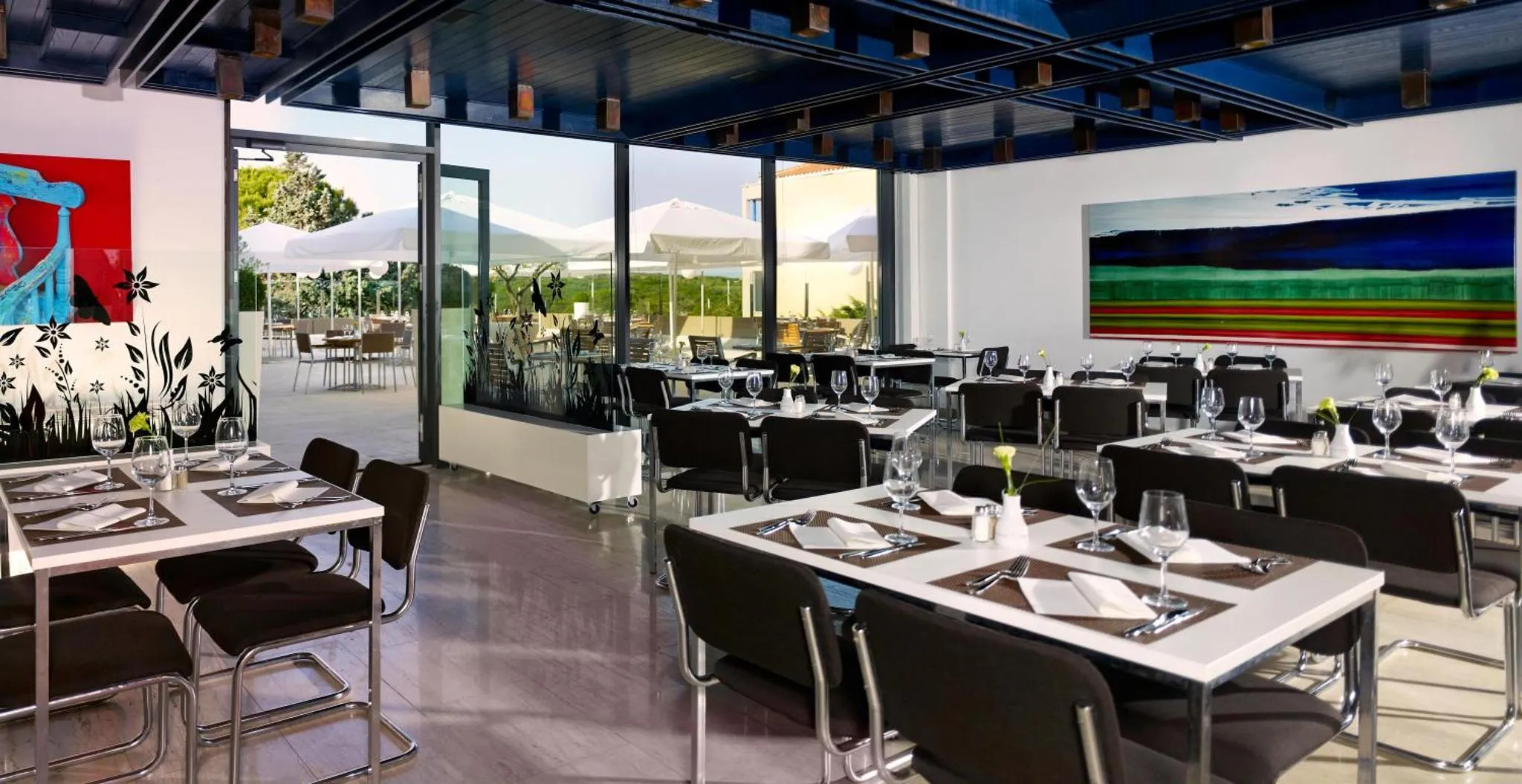Une salle de restaurant lumineuse avec des tables dressées et une vue sur une terrasse.
