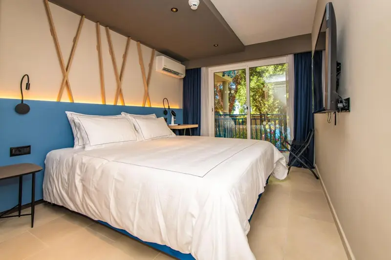 Une chambre lumineuse avec un grand lit et un accès à un balcon.