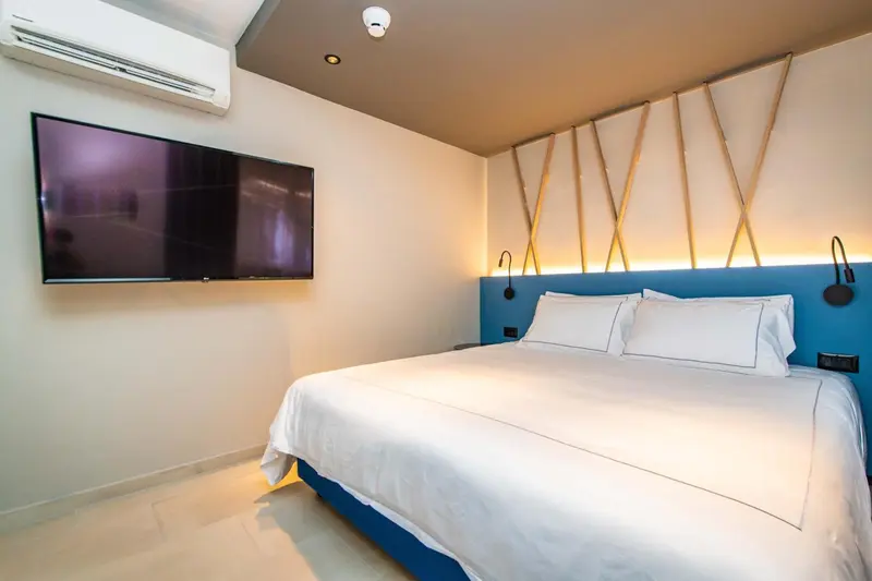 Une chambre lumineuse avec un grand lit et une télévision murale.