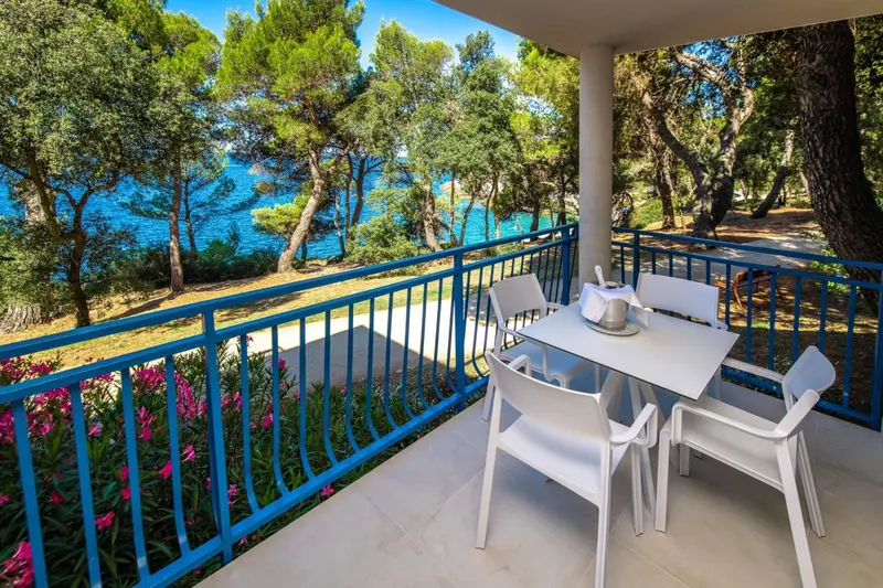 Terrasse avec mobilier blanc donnant sur la mer et la végétation.