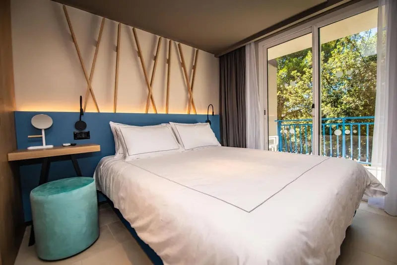 Une chambre lumineuse avec un grand lit et un accès à un balcon.