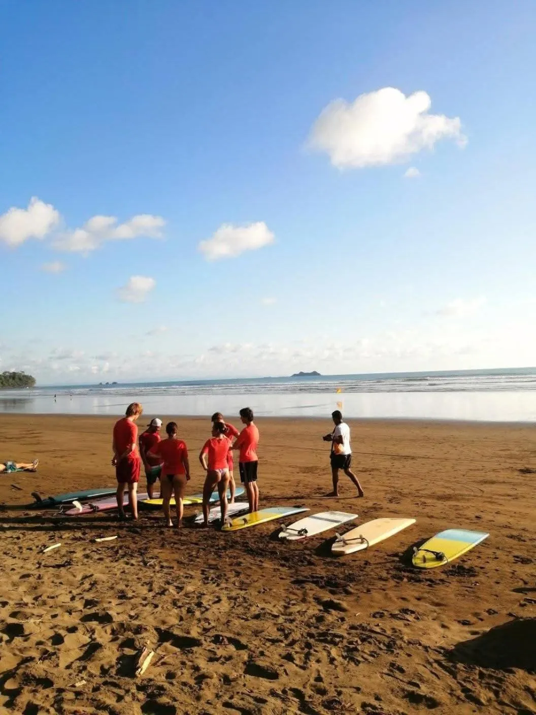 Un groupe de personnes se tient sur une plage de sable fin, devant la mer.